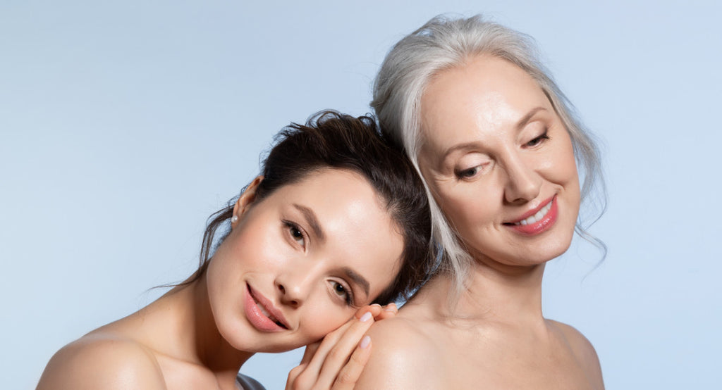 younger brunette woman rests head on shoulder of older grey haired woman
