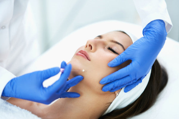 aesthetic doctor applying thread lift to face of brunette woman