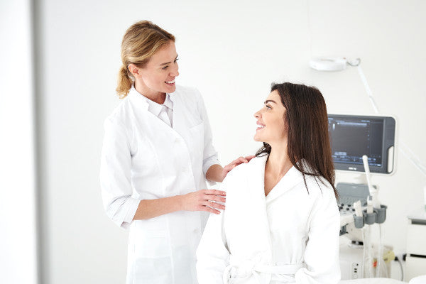 female doctor with seated client smiling in aesthetic treatment room