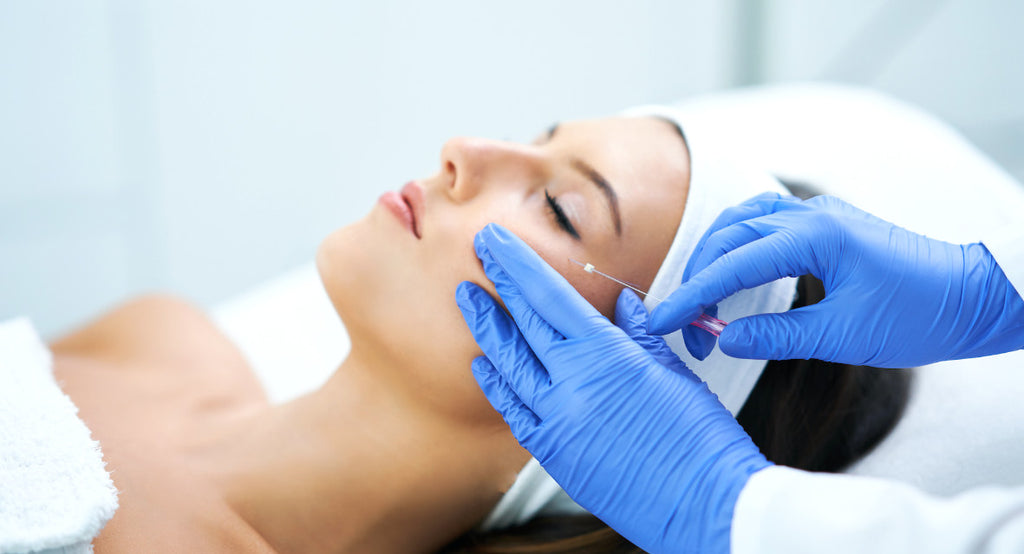 aesthetic doctor applying thread lift to face of brunette woman reclined on bed